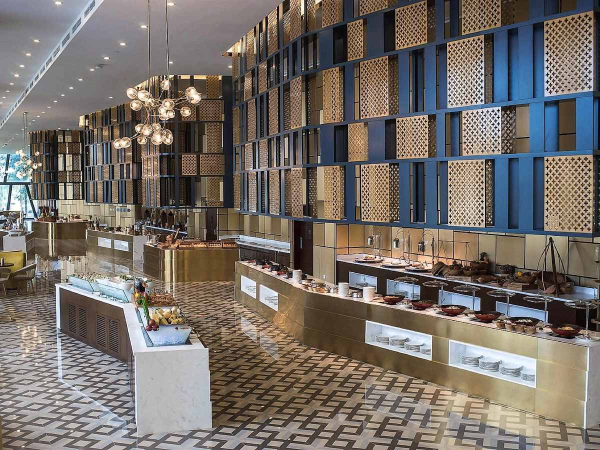 Long buffet counters in a restaurant with a patterned floor and tall blue and gold shelving