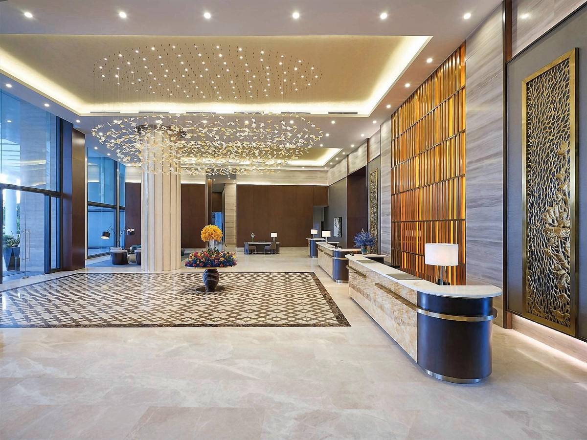 Bright marble lobby with a starry lit ceiling, gold screens and a curved reception counter