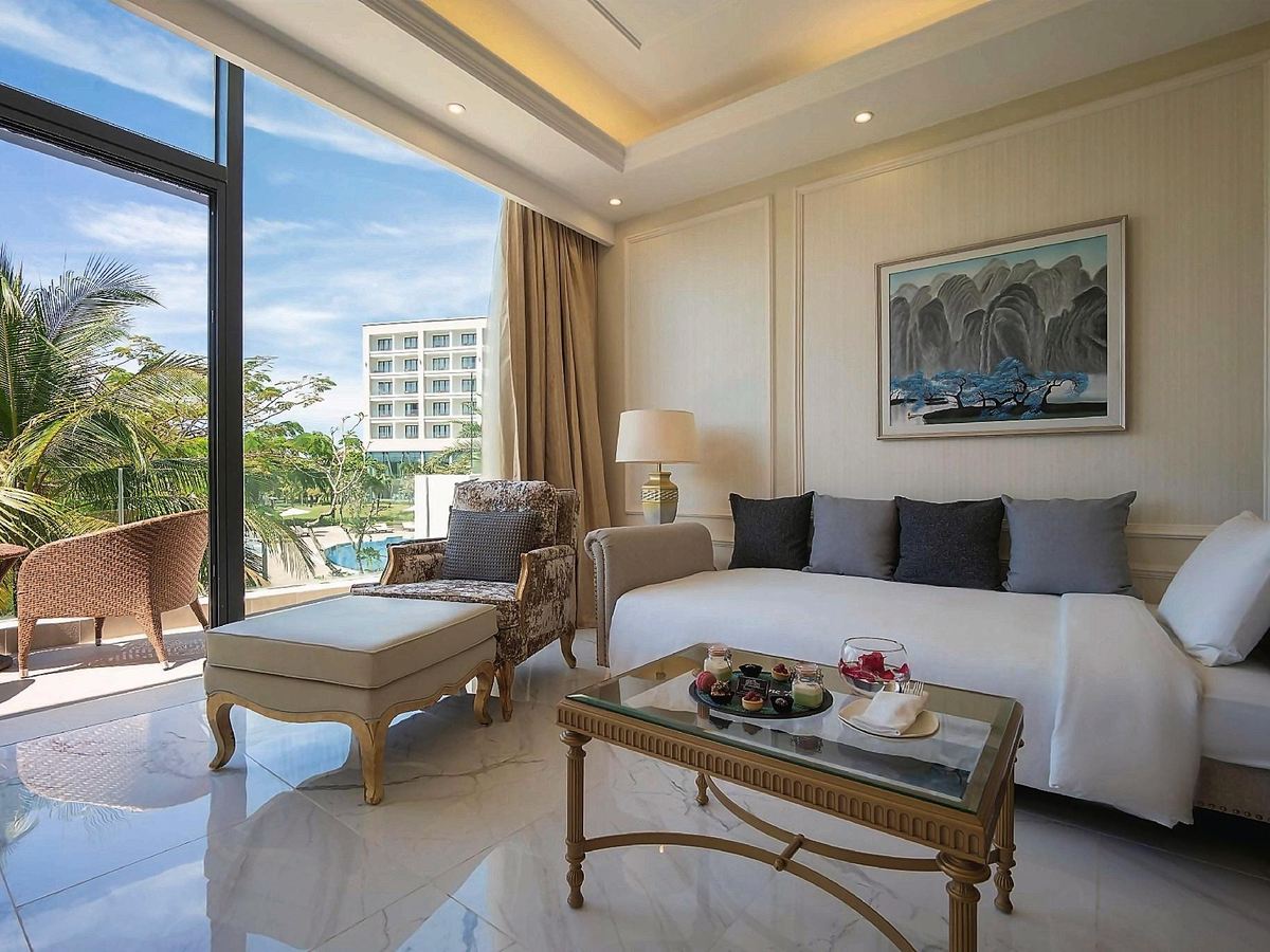 Loft living room with a beige sofa, marble floor and glass doors opening onto a palm garden