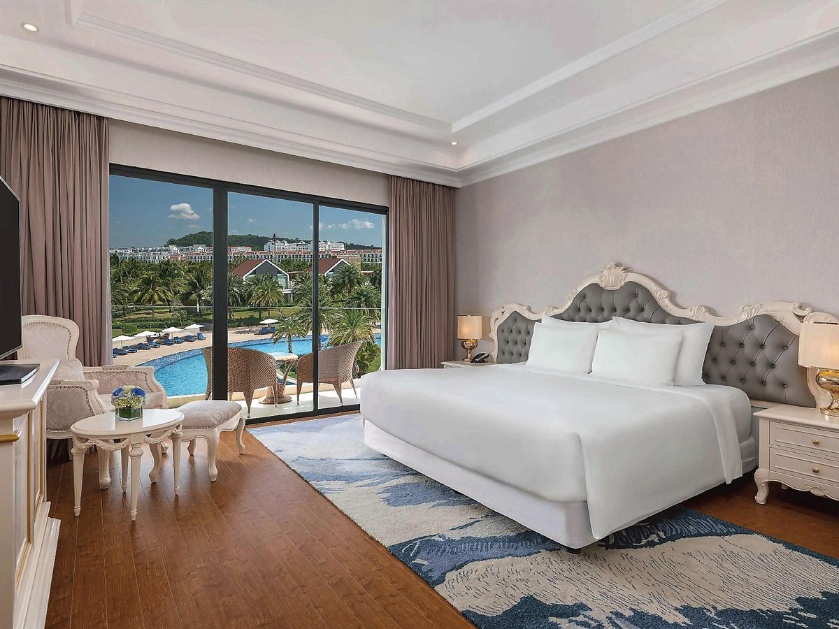 Deluxe room with a king bed, wooden floor and a balcony over the lagoon pool and palm gardens