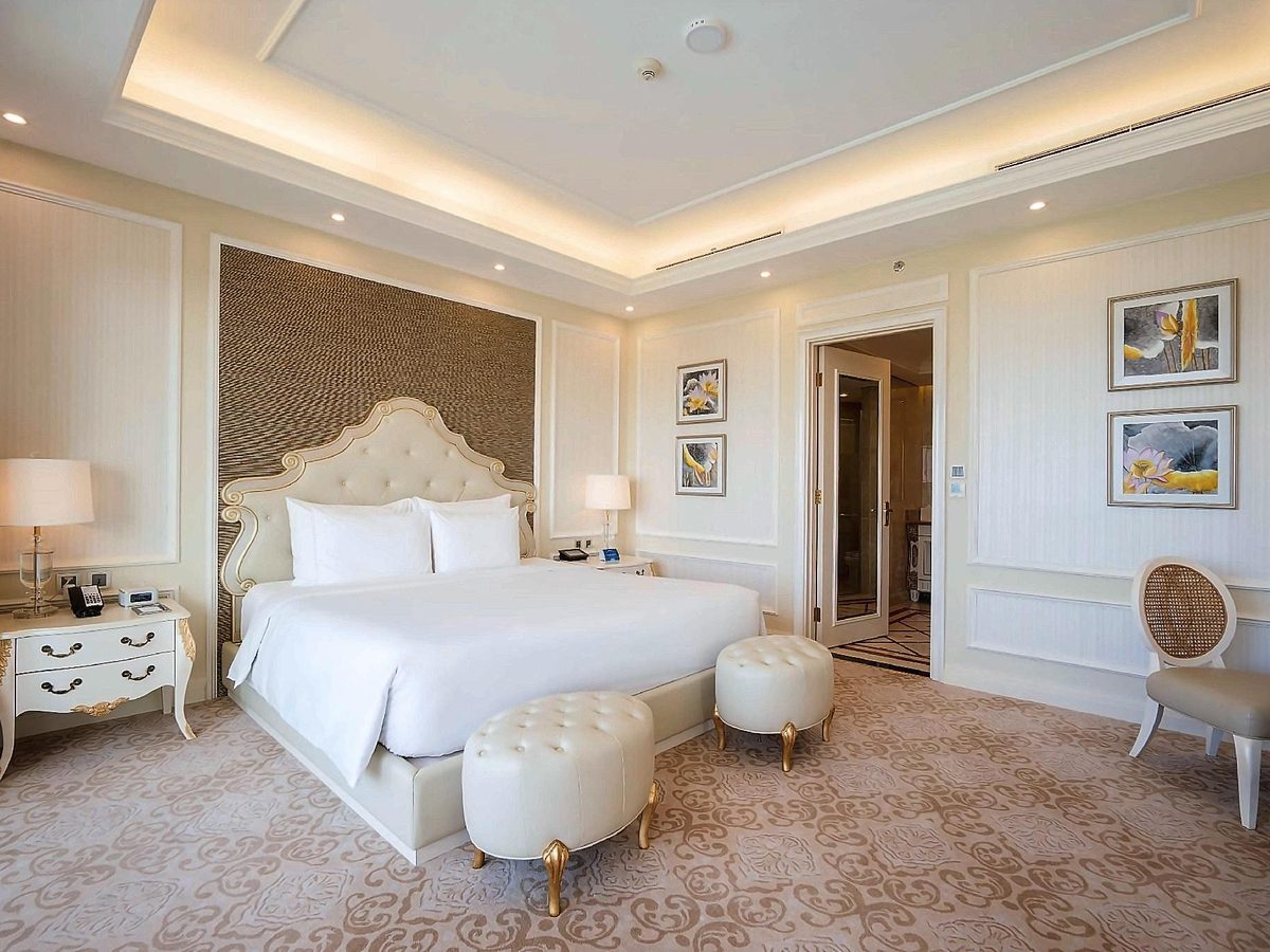 Top-floor suite bedroom with a carved headboard, cream walls and framed pictures beside the bed